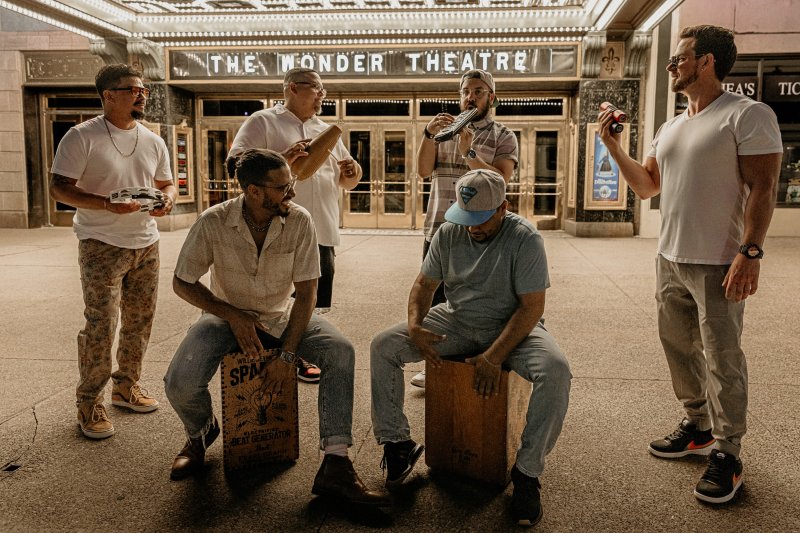 A group of men with instruments outside of a theater entrance
