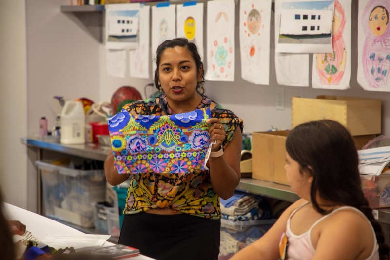 A woman holding up a piece of fabric in a workshop