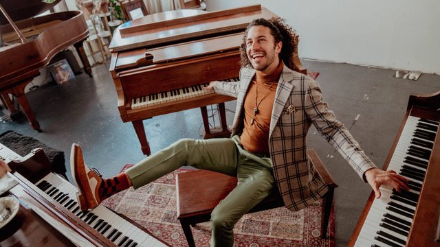 A man sitting on a piano bench playing three pianos with his hands and feet