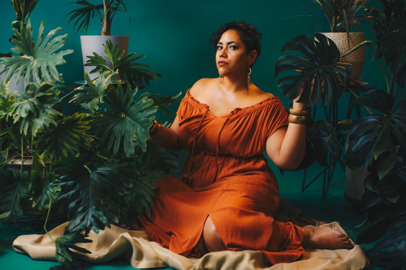 A woman in an orange dress surrounded by plants