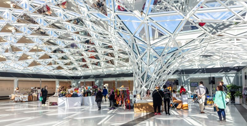 A group of vendors in a room with a glass mosaic ceiling that funnels into the ground
