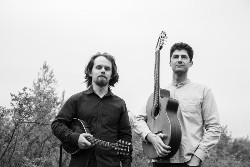 Black and white image of two people outside with guitars