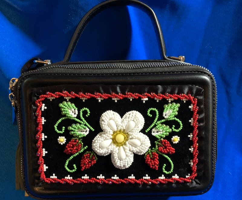 A black beaded purse in front of a blue backdrop