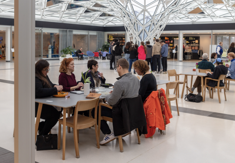 People sitting at tables under a glass mosaic canopy ceiling