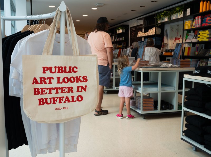 A museum shop with a bag at the forefront that reads "Public Art Looks Better In Buffalo" 