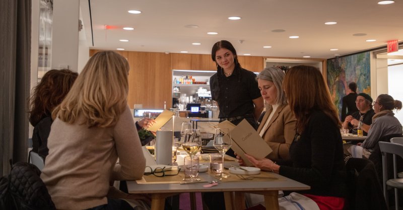 A group of people dining in a restaurant and speaking with a waitress