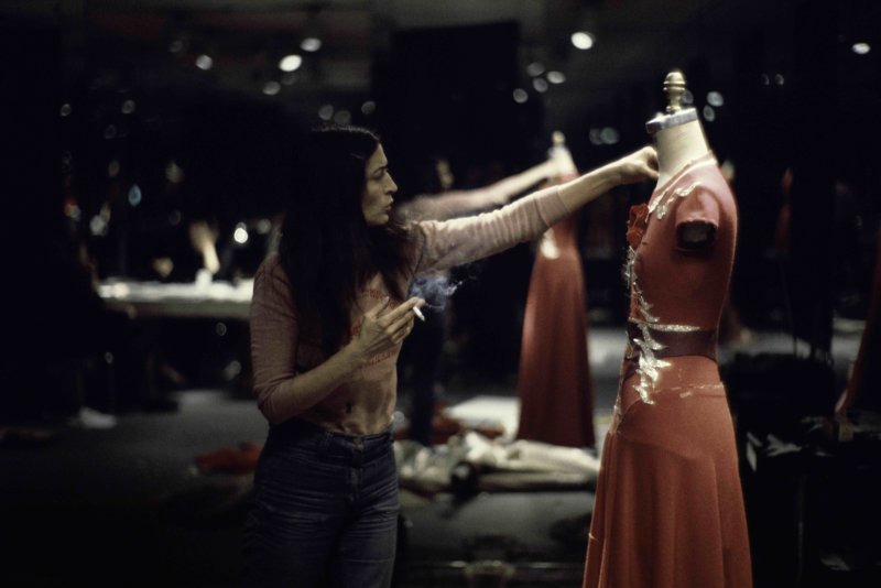 Artist Marisol touching up a costume on a mannequin 