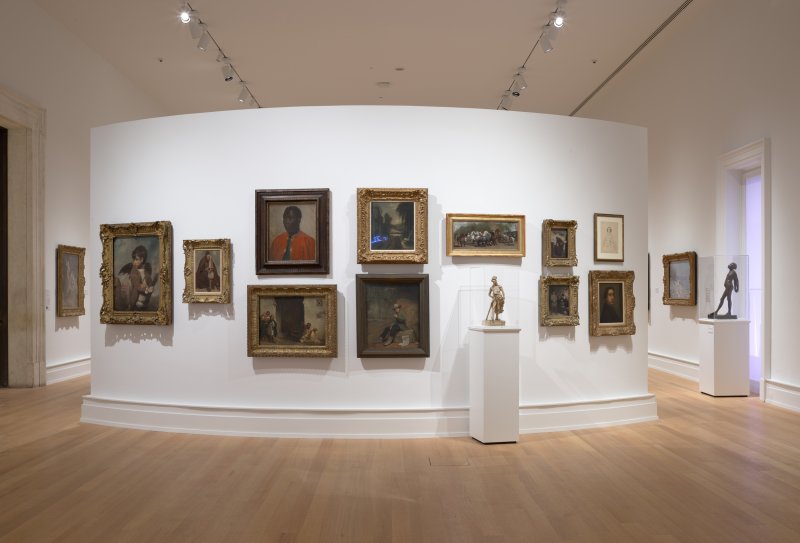 A salon-style wall of various paintings