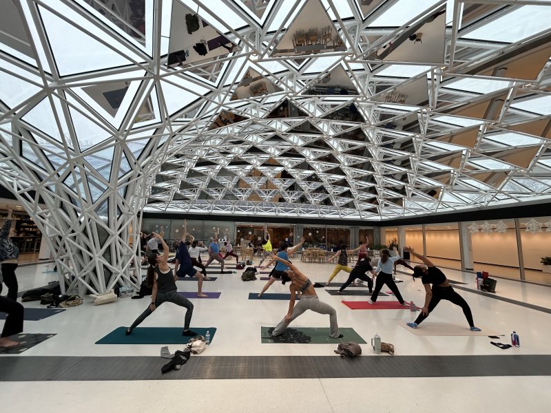 A group practicing yoga under a glass mosaic ceiling