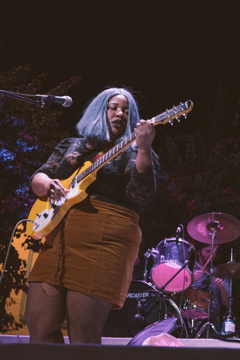 A person performing on stage with a guitar