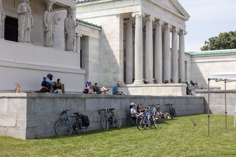 People reading around a marble museum building outdoors