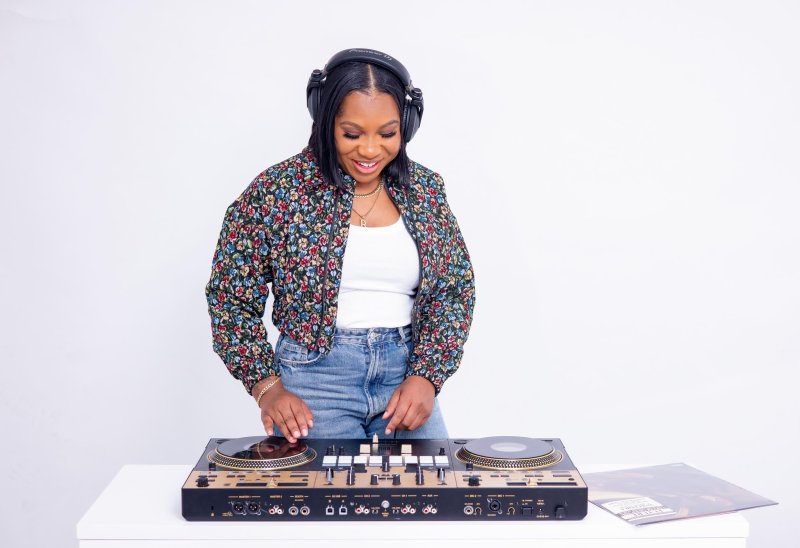 A DJ performing in front of a white wall