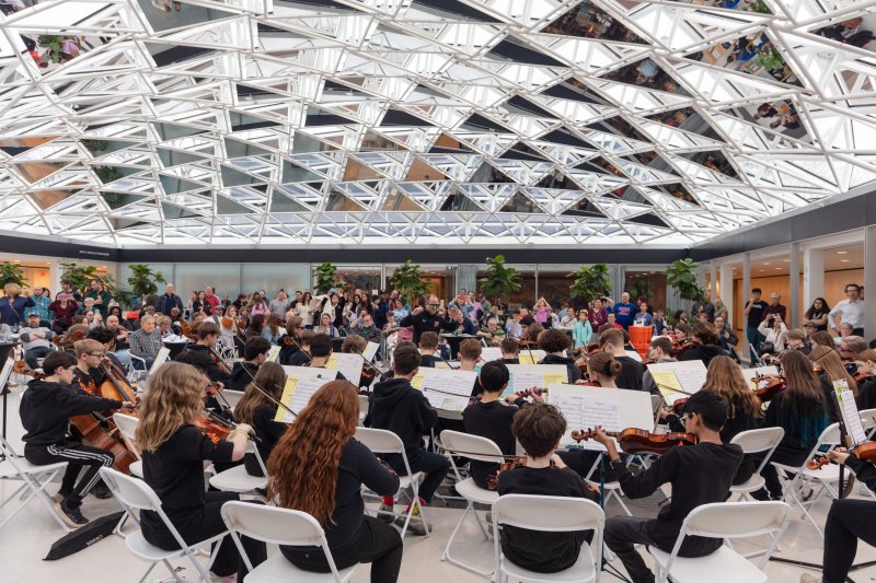 A student orchestra performing under a glass mosaic ceiling