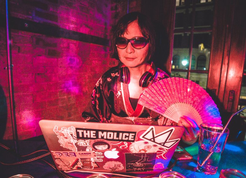 A person wearing sunglasses in front of a laptop computer