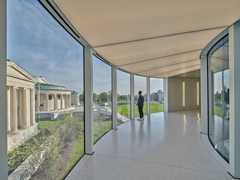 A person walking on a bridge with glass walls on either side