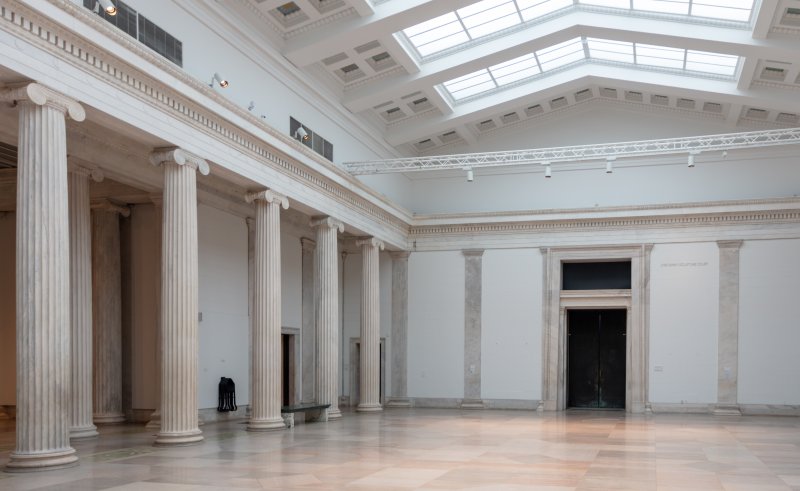 A large room bordered by columns and covered by a translucent ceiling