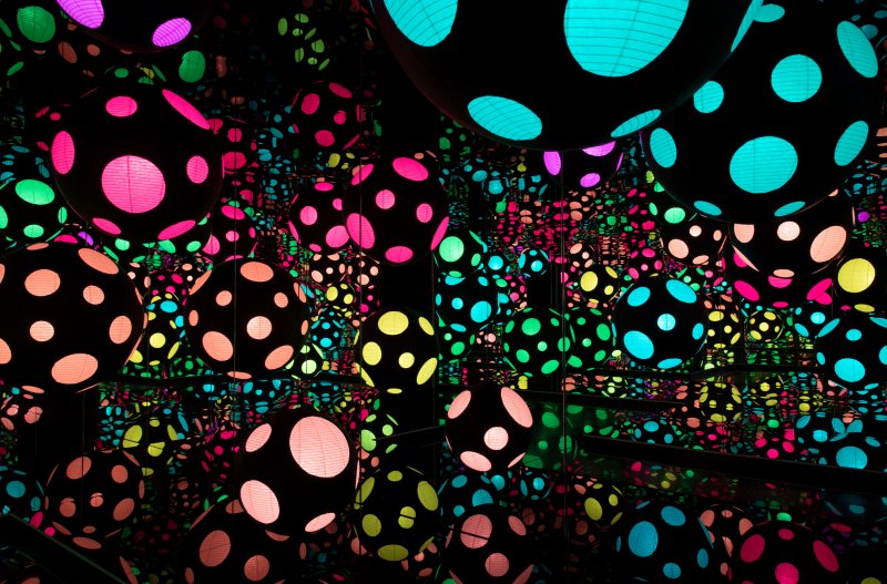 Dark mirrored room with black orbs with vibrant lit polka dots