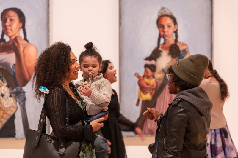 Women and children in front of two paintings depicting women