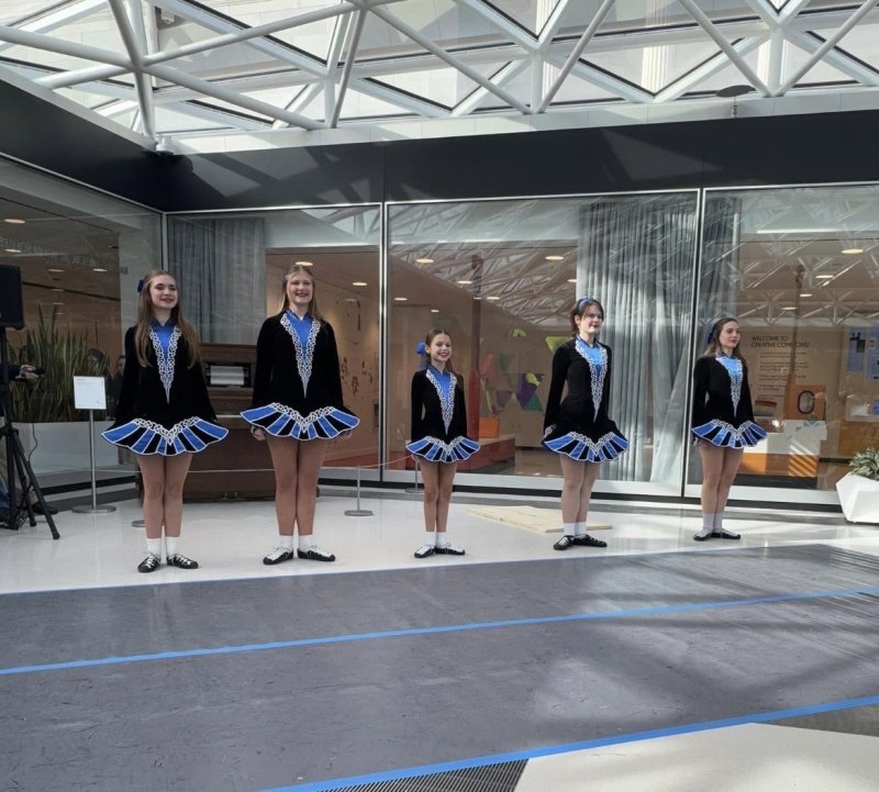 Irish dancers lined up in a brightly lit room