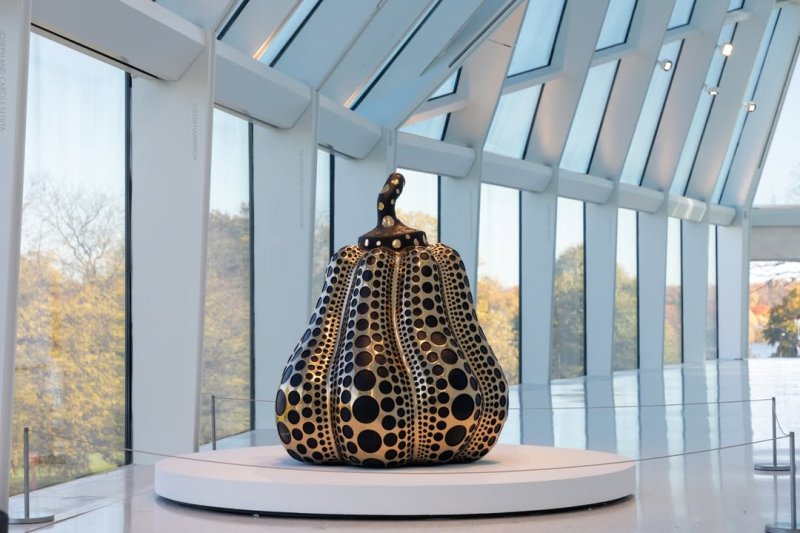 Installation view of a sculptural pumpkin on a white circular stand
