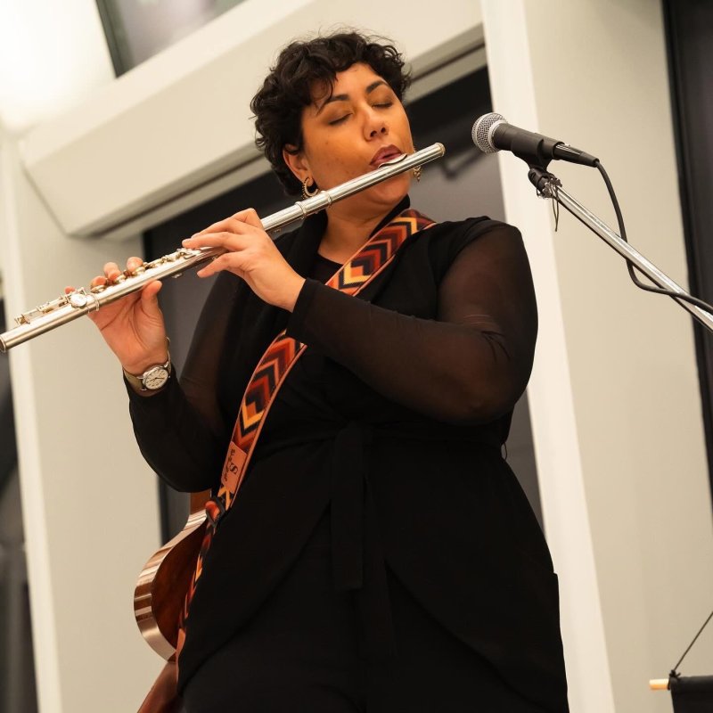 A woman playing a flute in front of a microphone on a stand