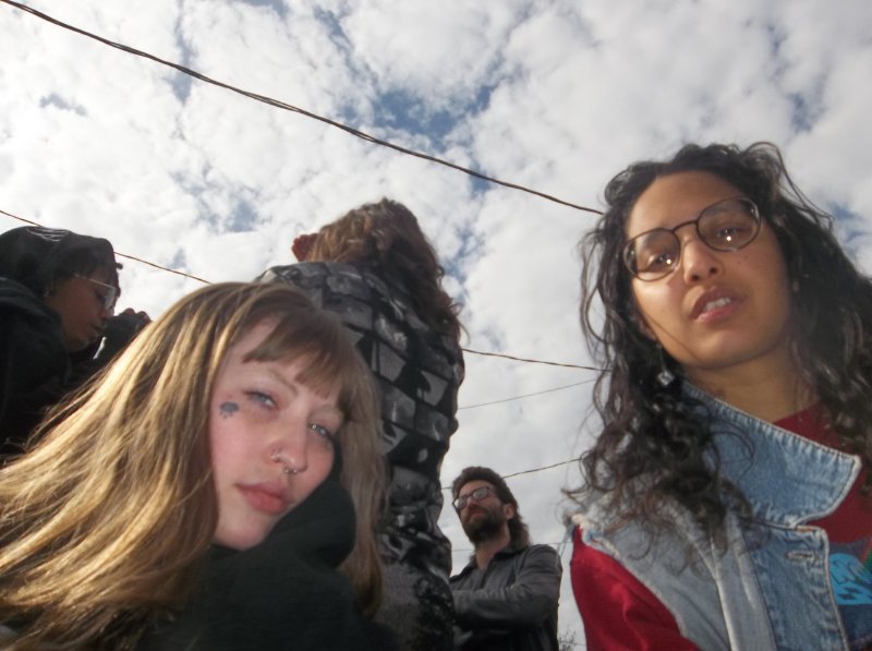 Photo of two people looking directly into the camera with white clouds behind them