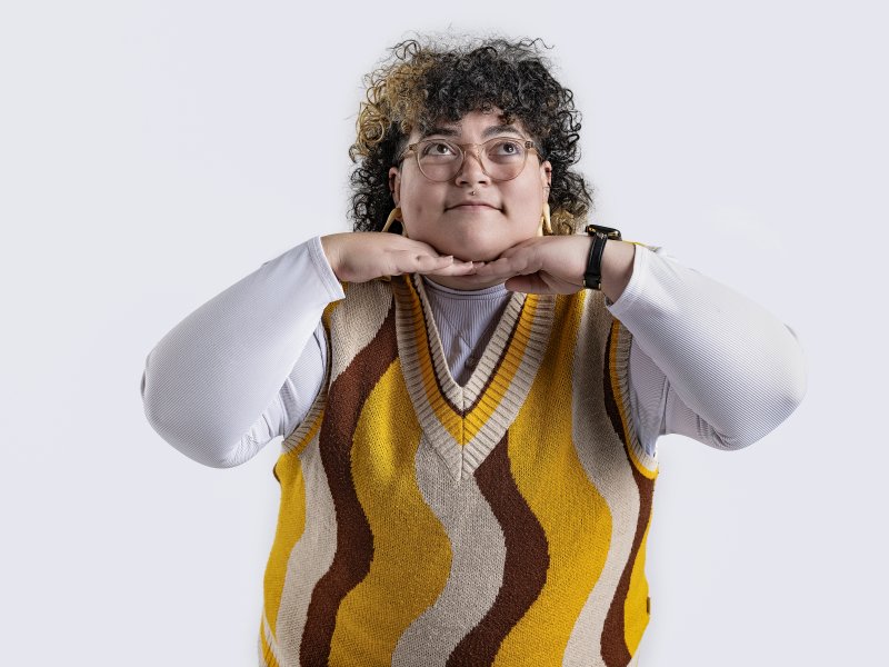 A person smiling with their hands under their chin