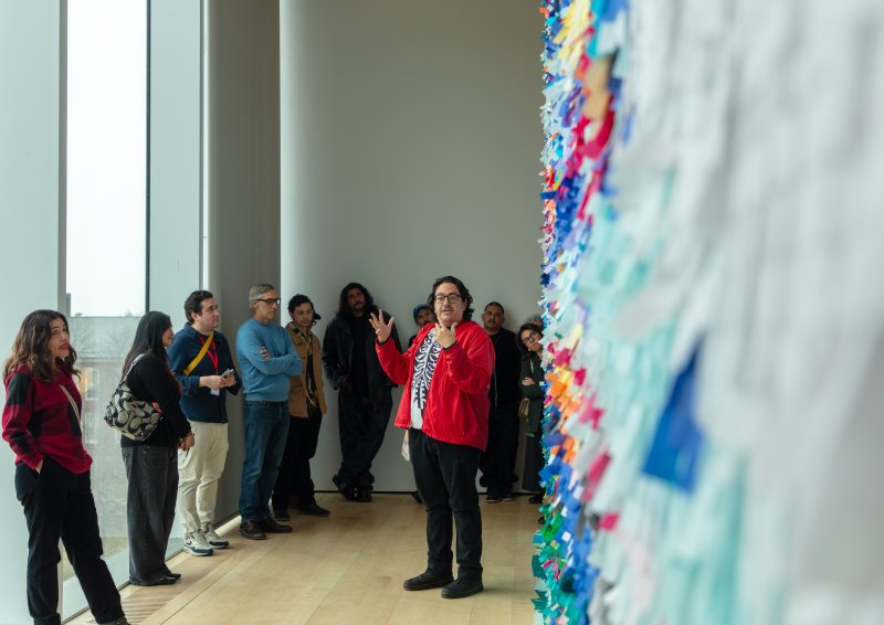 An artist leading a tour in front of a large, colorful wall