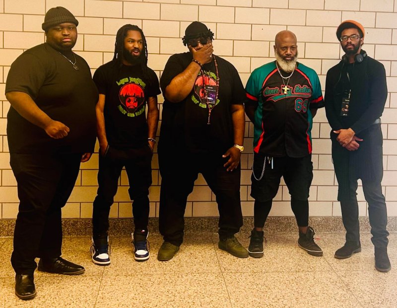 Five adults dressed in black standing side by side