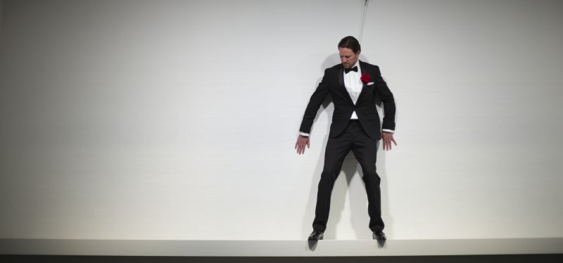 A person in a tuxedo scaling a wall 