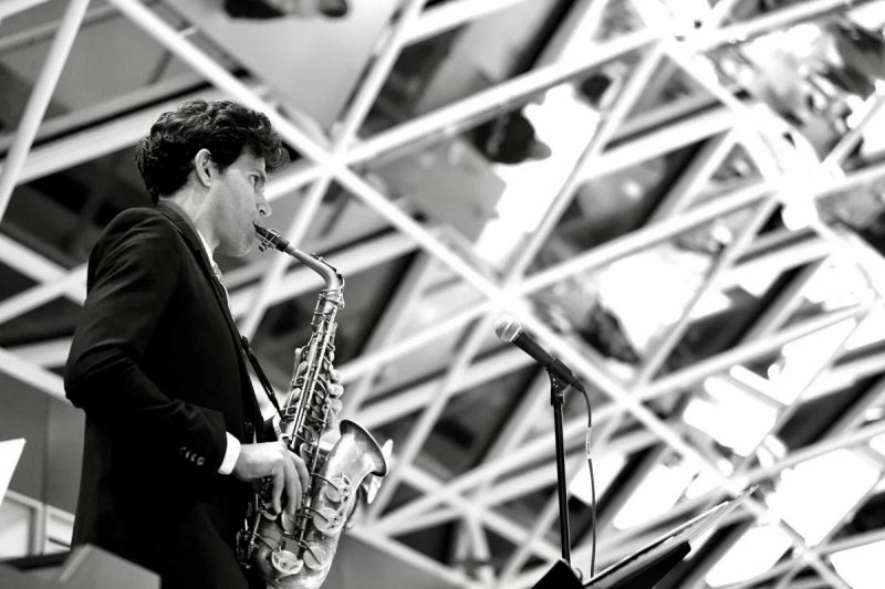 A black-and-white image of a man playing a saxophone