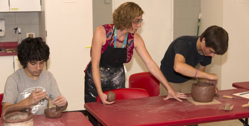 An AK educator assists teens in a sculpture project