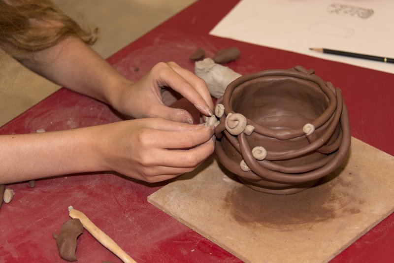 Hands molding a clay pot