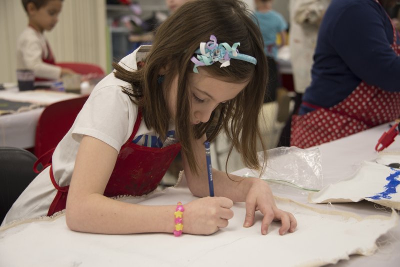 A girl drawing on a large piece of white paper
