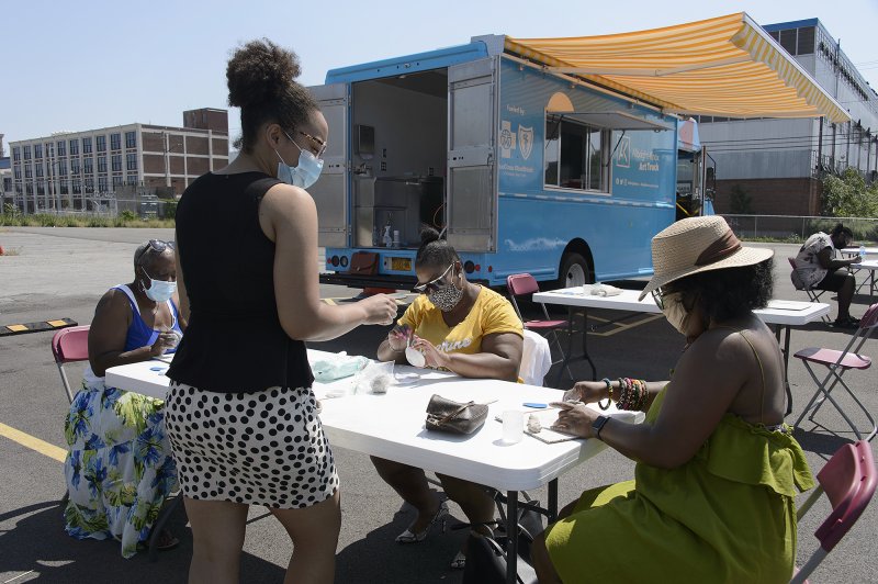 Four Black women making art around a table outside