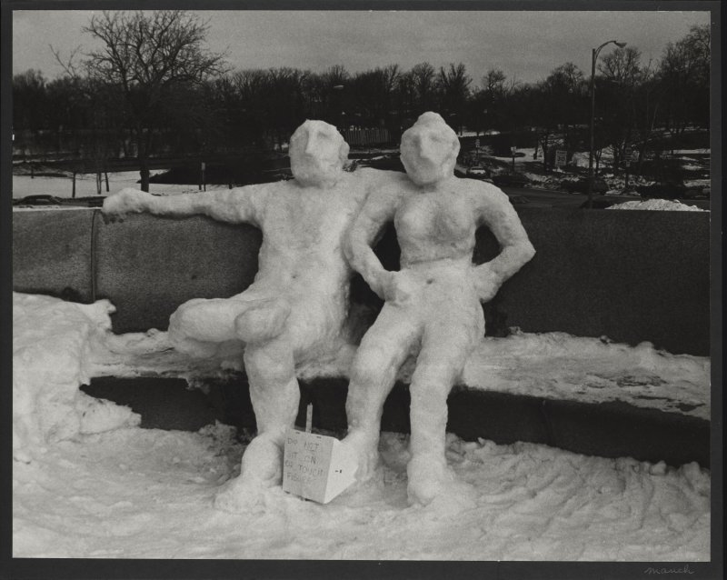 Snow sculpture of two people sitting on a bench