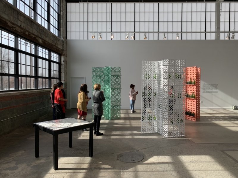 Teenagers standing among three wooden screens, one green, one white, and one pink