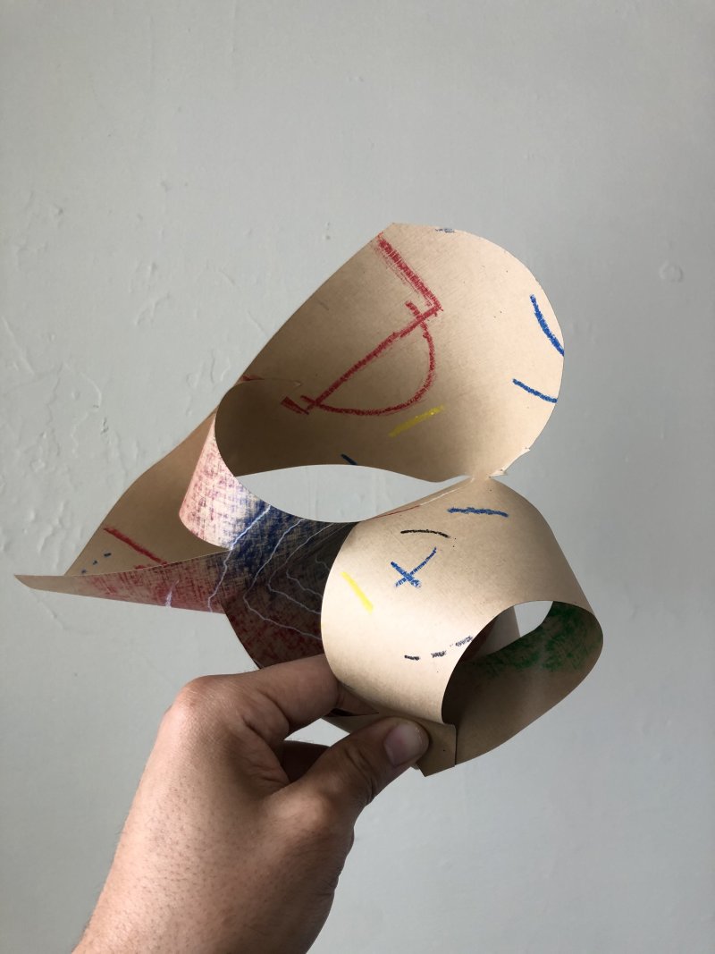 A hand holding up a paper sculpture