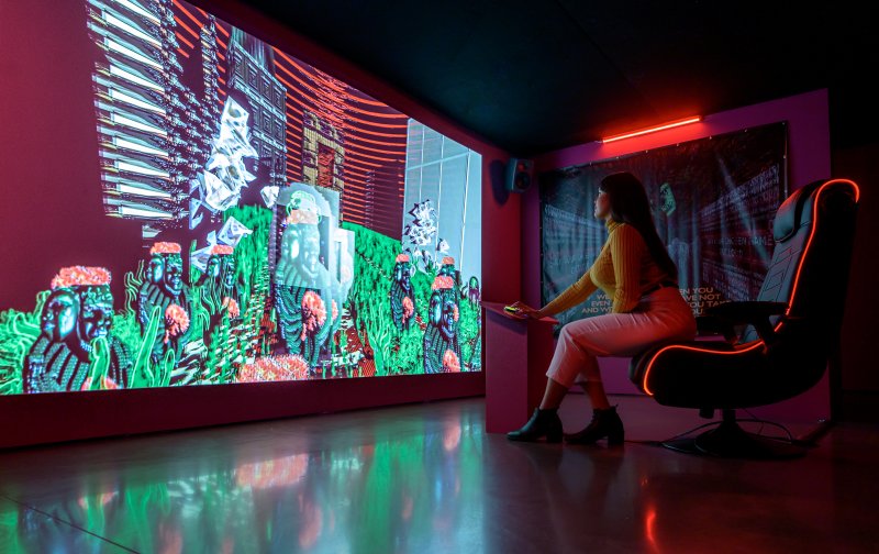 A person sitting in a chair looking at a large digital screen that takes up an entire wall