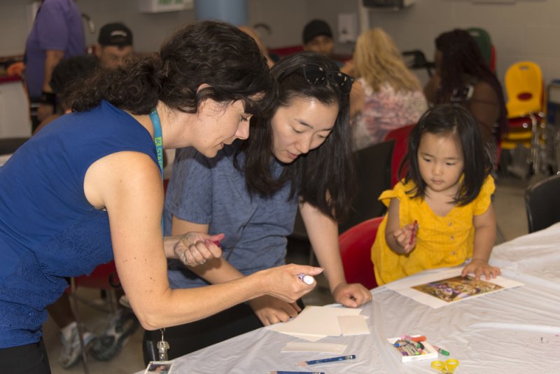 Teacher helping a mom and daughter make art in the classroom