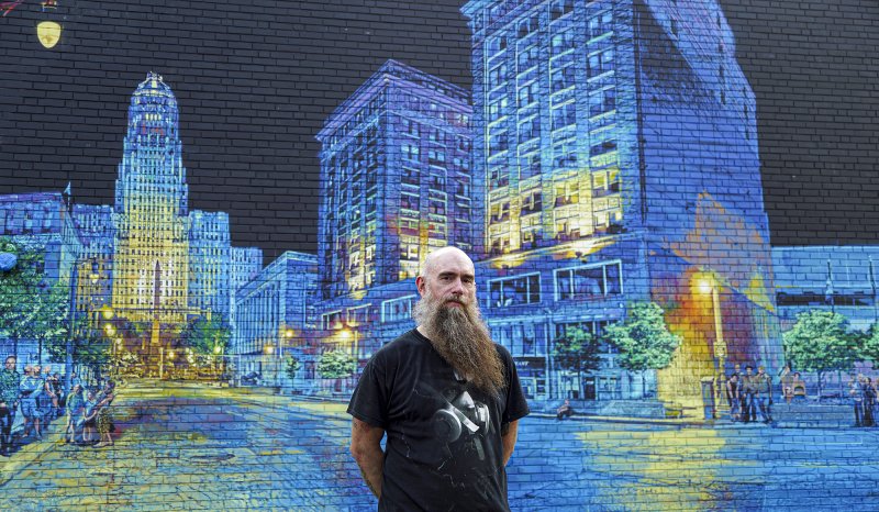 Logan Hicks in front of his mural