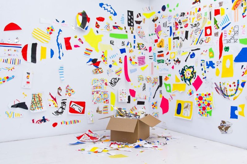 Pieces of paper with colorful markings on them fastened to a white wall