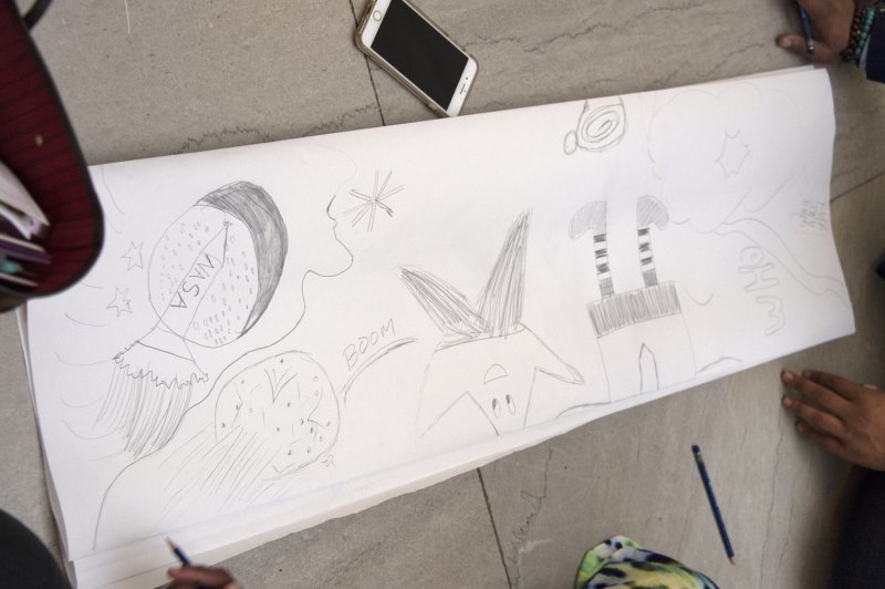 A pencil drawing on a long sheet of paper on the floor