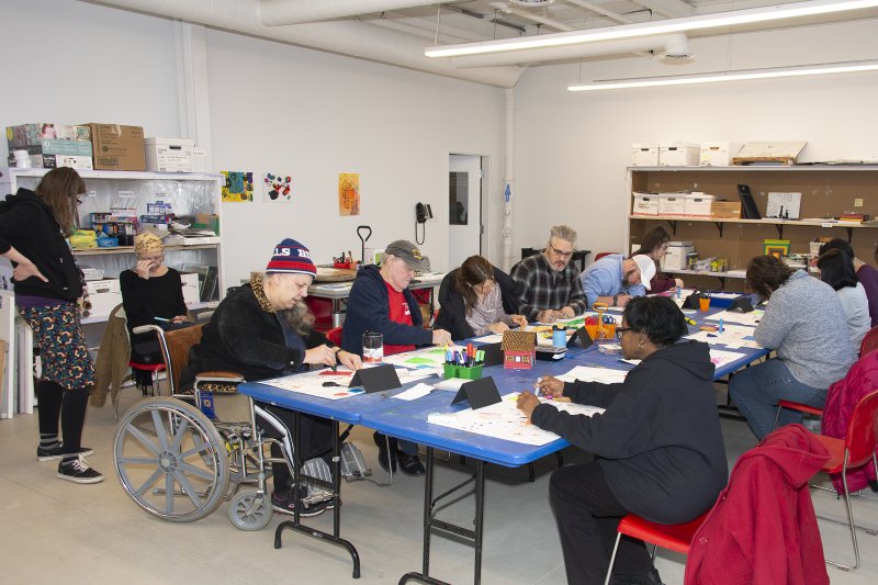 A group of adults making art in a classroom