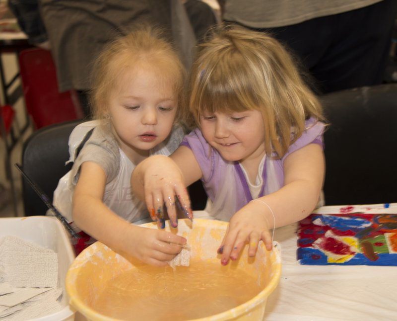 Two young girls work on a bowl in the classroom