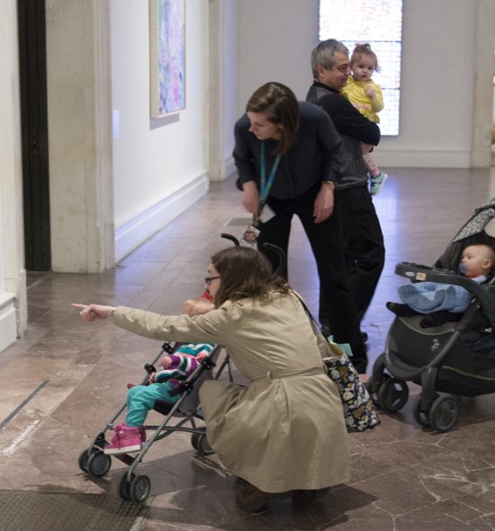 Parents with children in strollers looking at art