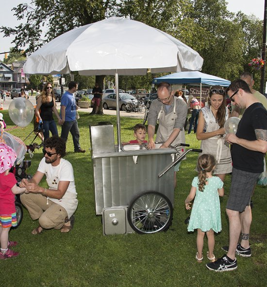 People gathered around a silver cart with an umbrella on top