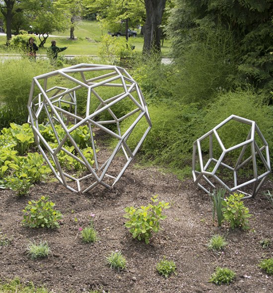Silver spherical shaped sculptures placed outside among plants