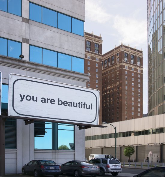A large white billboard with the words "you are beautiful" in large black letters