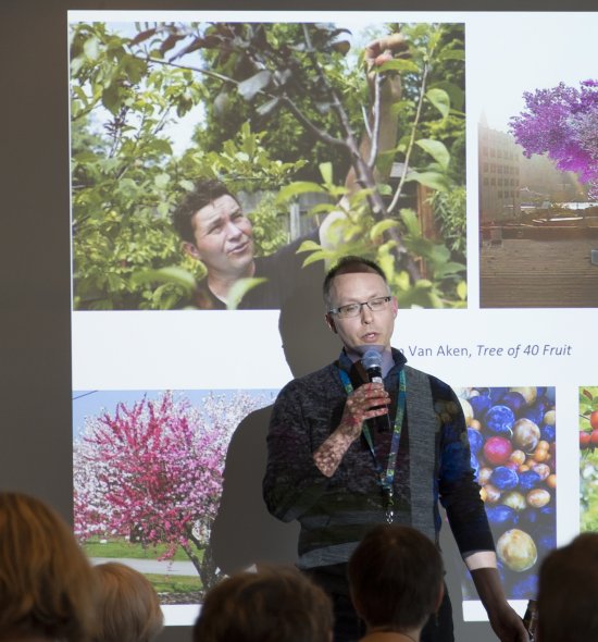 A man standing in front of a screen with images of flowering trees projected on it